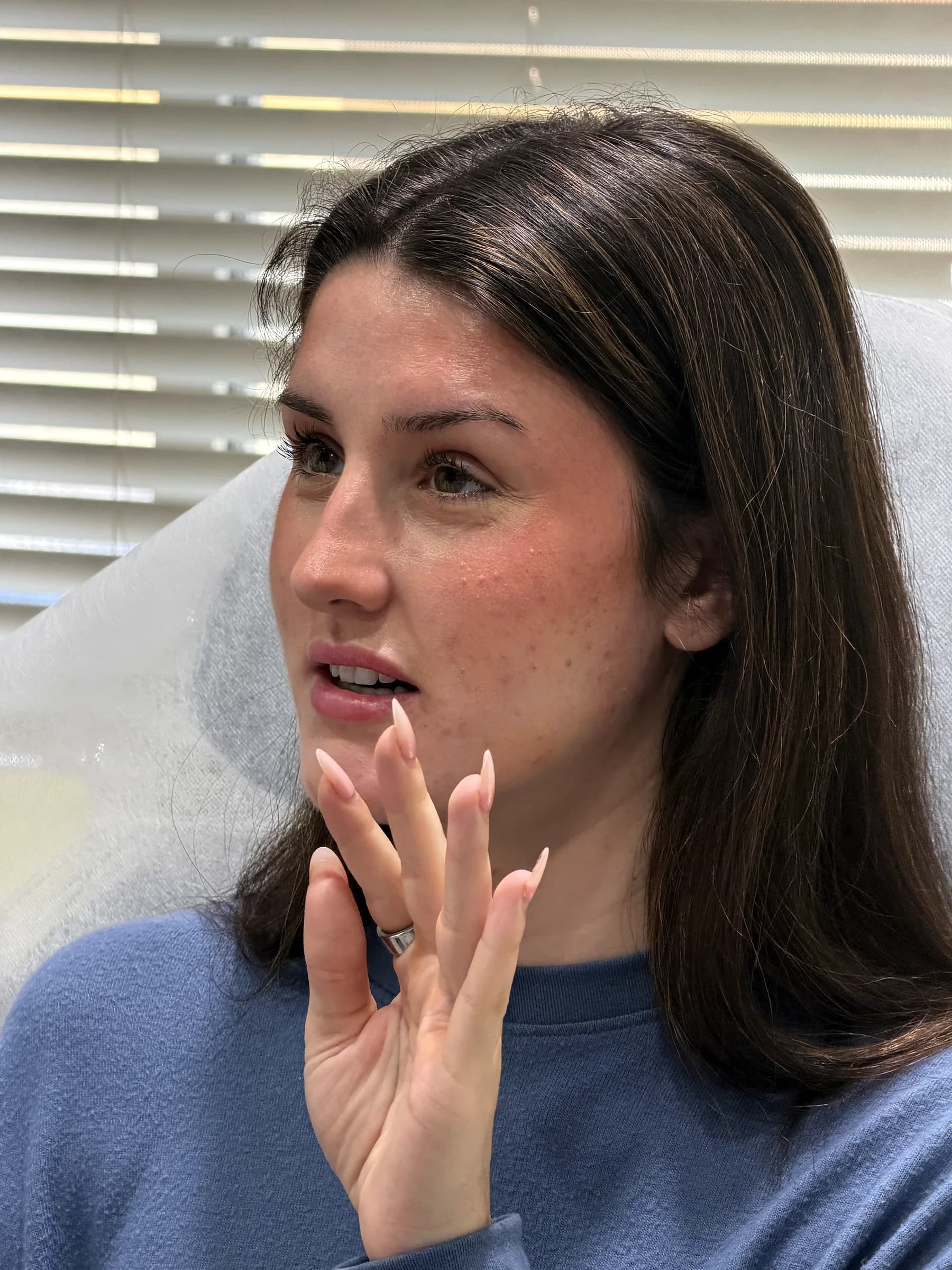 A patient points to the cheek and jaw area during a facial balancing consultation