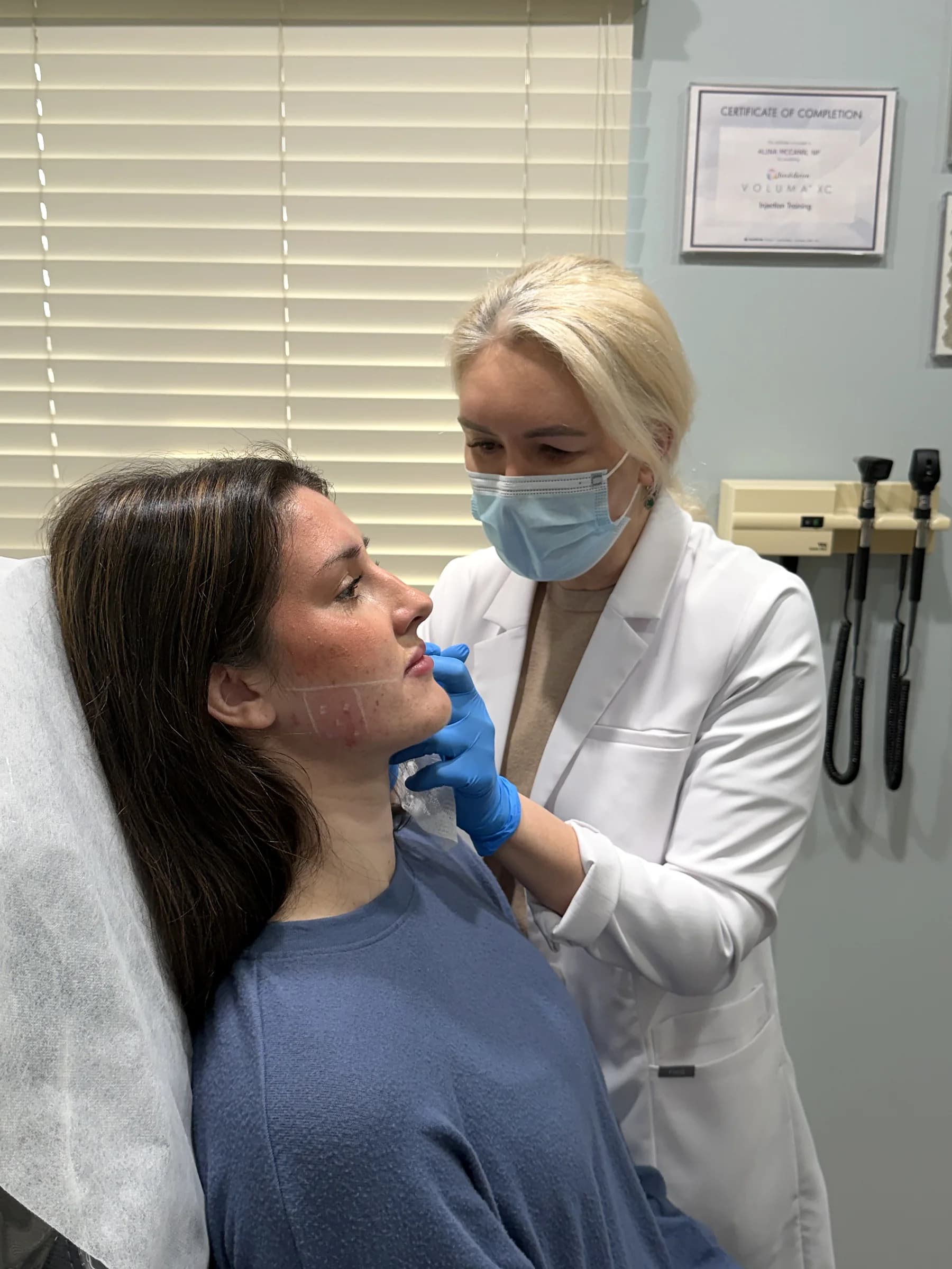 Alina McCann assessing a patient's chin and jaw before filler