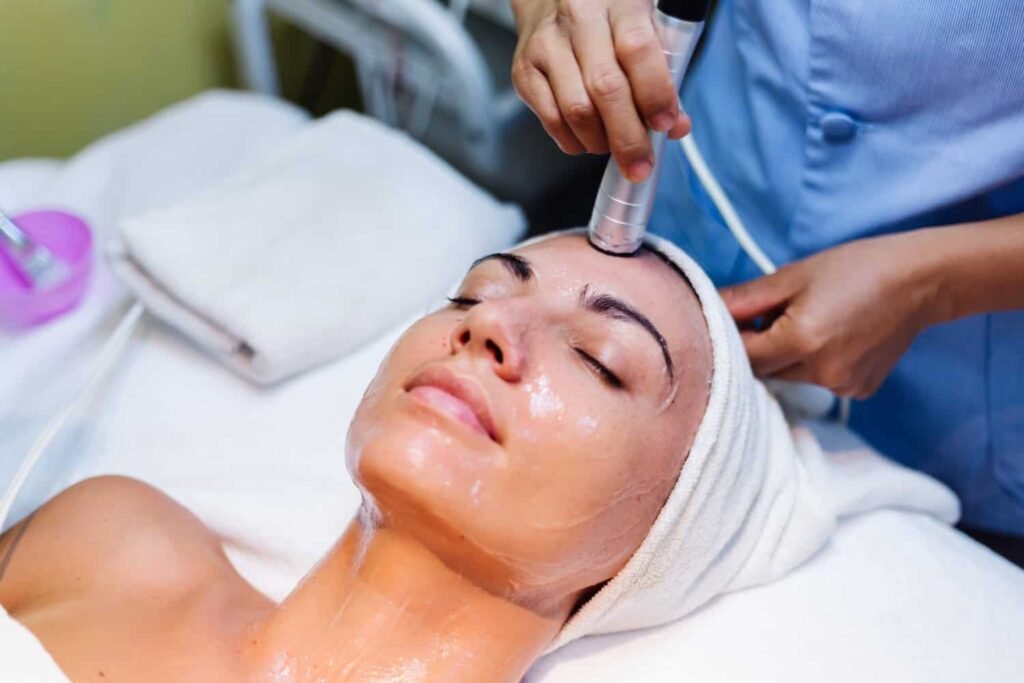 Professional administering HydraFacial treatment on client, showcasing skincare process for deep cleansing and hydration, with focus on rejuvenation and glowing skin.