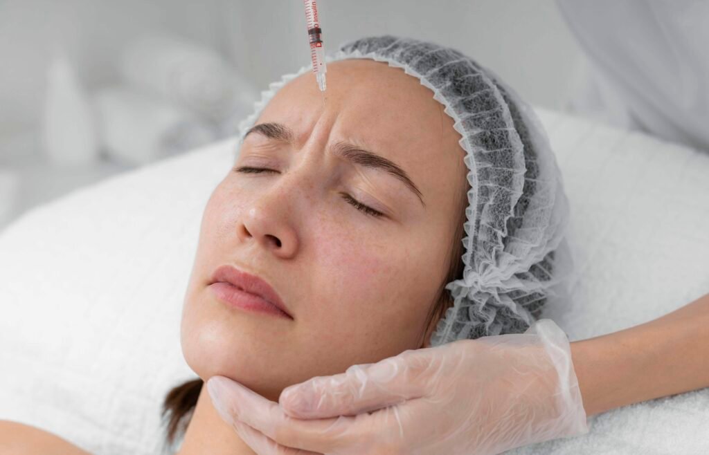 Woman receiving microneedling treatment with Vi Peel, wearing a hairnet, lying on a treatment bed, with a practitioner administering the procedure.